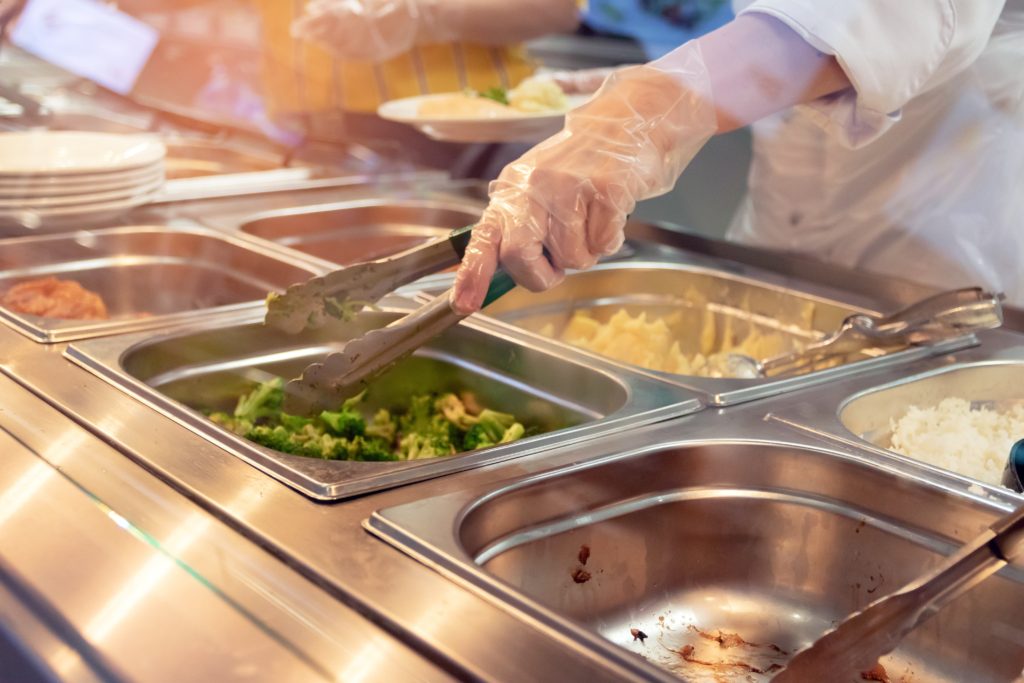 worker serving food at lunch buffet.