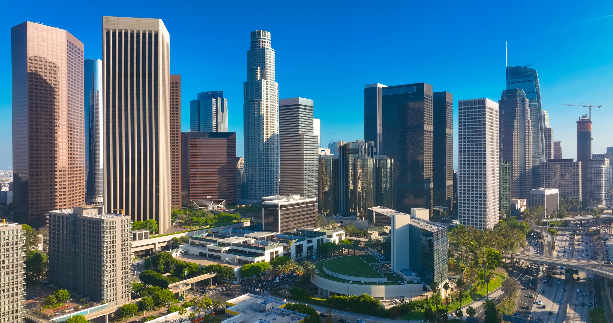 Los Angeles city. LA downtown aerial view. Los Angeles skyline. LA streets. Los Angeles from a top view. Downtown towers of Los Angeles. Panoramic scene of LA skyline. Blue sky frames the city below. Los Angeles city